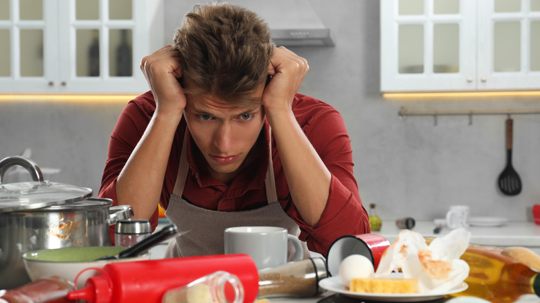 Man with his head in his hands looking confused in the kitchen