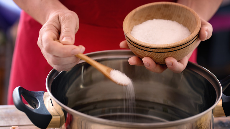 Person adding salt to a pot of water