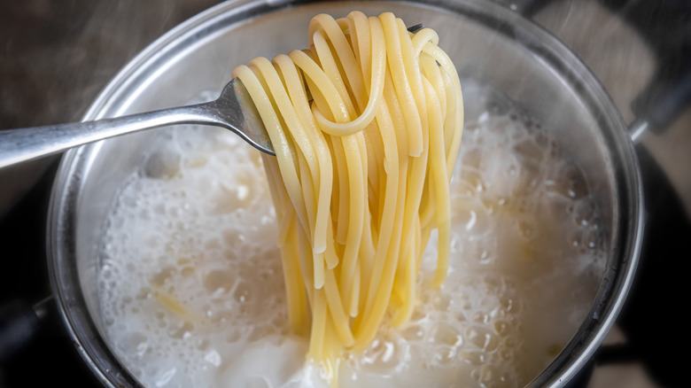Spaghetti-esque noodles being pulled from a boiling pot