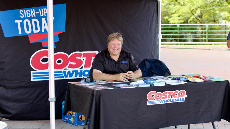 A Costco employee at a booth, selling Costco memberships