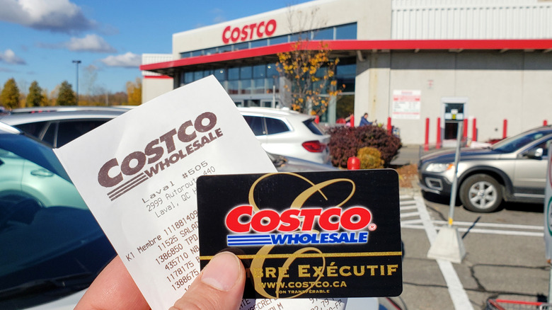 A hand holding a Costco Executive membership card alongside a receipt from Costco