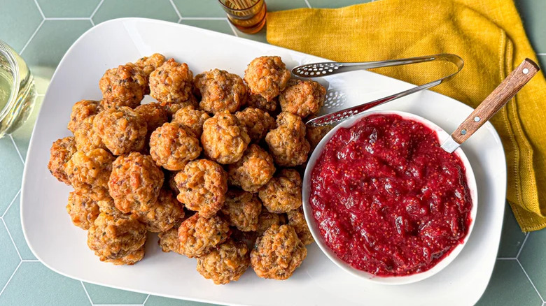Rectangular white platter with Classic Sausage Balls With Cranberry Mustard in white ramekin