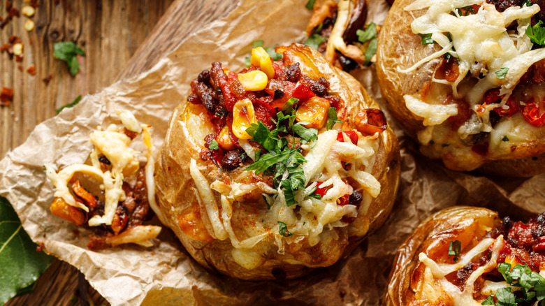Overhead view of Mexican style baked potatoes with corn, cheese, salsa, and bacon