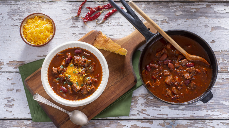 Overhead view of a bowl and cast iron pot full of bean and beef chili
