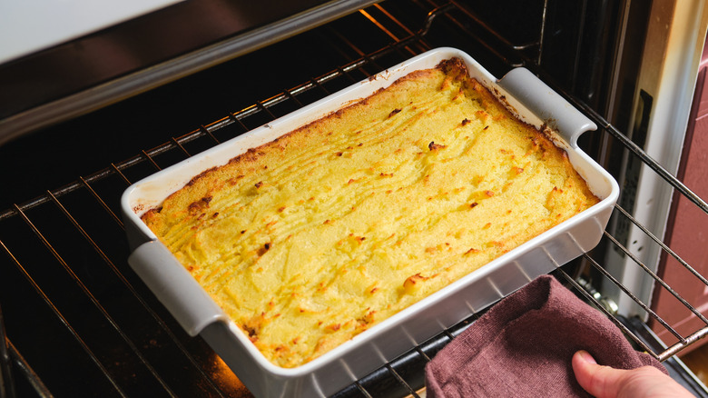 Person pulling out shepherd's pie from oven