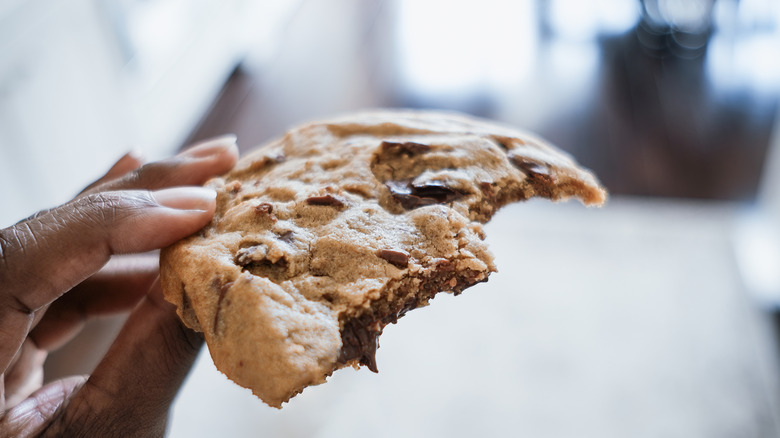 Person holding a chocolate chip cookie in their hands