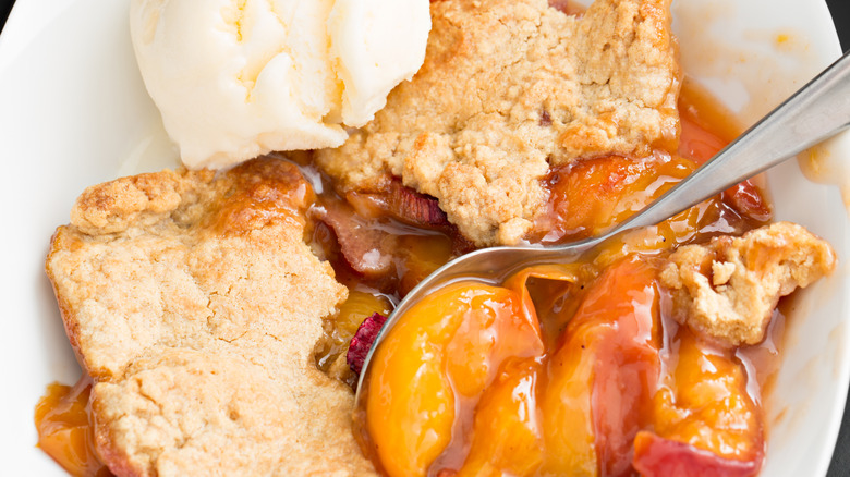 Peach cobbler on a white plate with vanilla ice cream