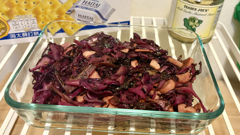A red cabbage salad with chopped Vienna sausages in front of some mustard and saltines