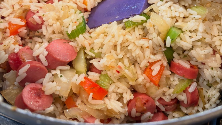 A close up of Arroz Con Salchichas being stirred in a pan