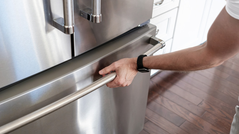 Person grabbing freezer drawer on stainless steel fridge