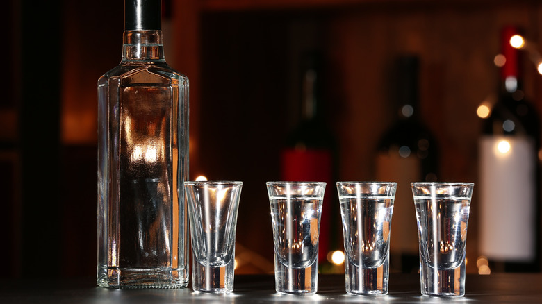 bottle of cold vodka and shot glasses on a bar