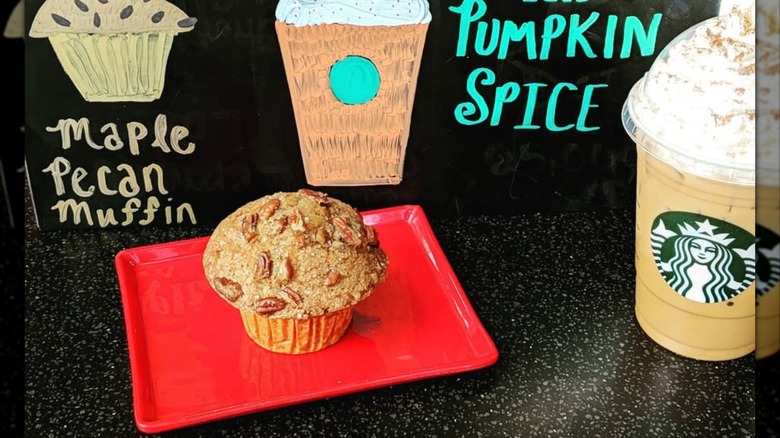 Starbucks' Maple Pecan Muffin on a red tray in front of drawings of the muffin and a Pumpkin Spice Latte