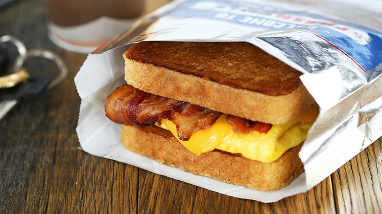 Sonic's French Toaster Breakfast sandwich in a foil wrapper. There is a coffee cup and car keys next to the sandwich.