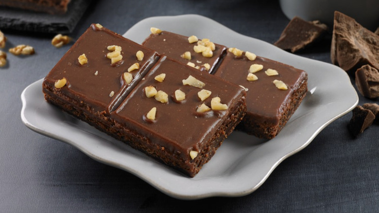 Two Little Debbie Fudge Brownies with English Walnuts sit on a white plate.