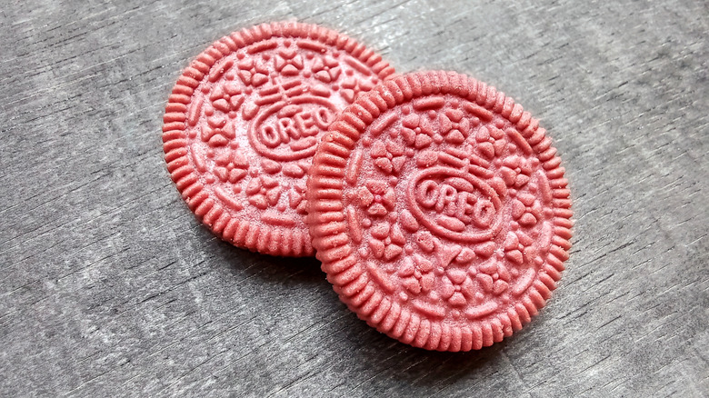 Two red velvet Oreo cookies on a grey background