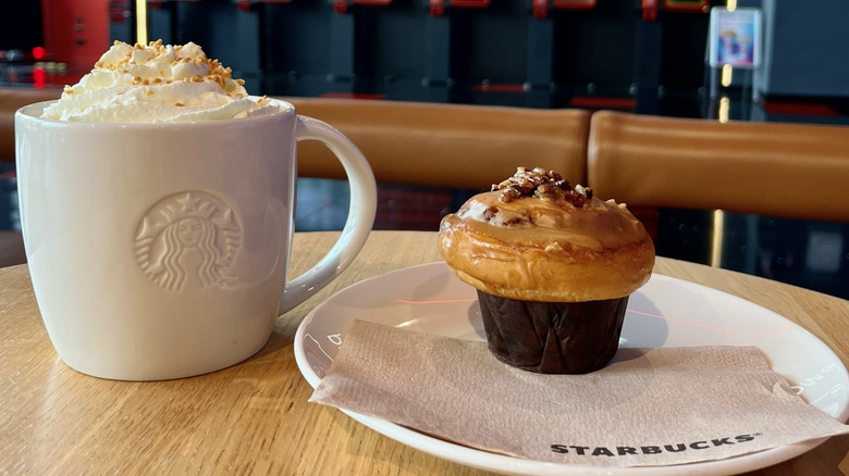 A Maple Pecan Latte in a Starbucks mug next to a peacan muffin on a plate