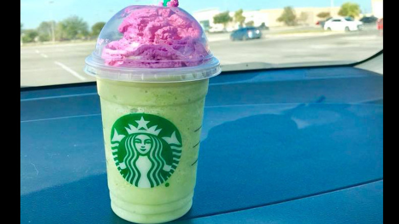 A zombie frappuccino from Starbucks on a car dashboard in a parking lot