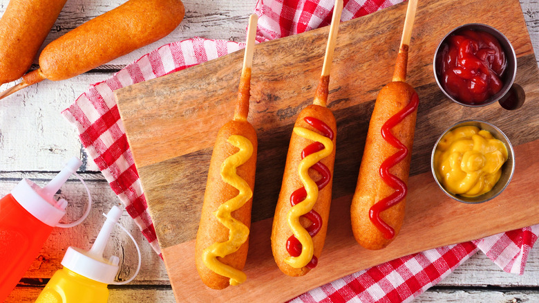 Three corn dogs with ketchup and mustard