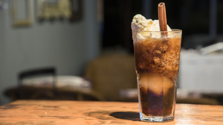 A root beer float garnished with a cinnamon stick