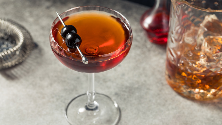 A mezcal Manhattan cocktail garnished with cherries