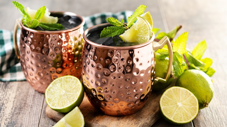 Two mezcal mule cocktails garnished with lime and mint