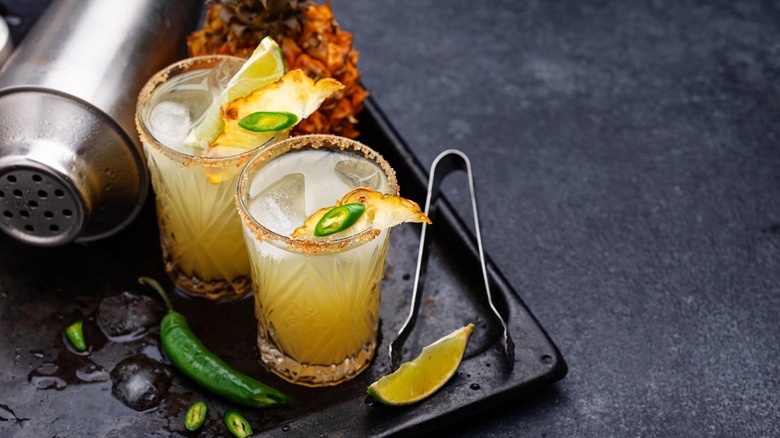 Two mezcalita cocktails garnished with lime, pineapple, and jalapeño