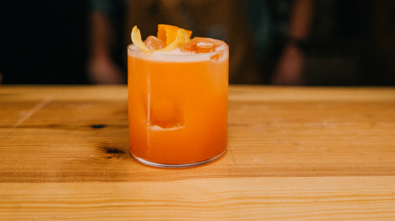 A naked and famous cocktail garnished with orange peel