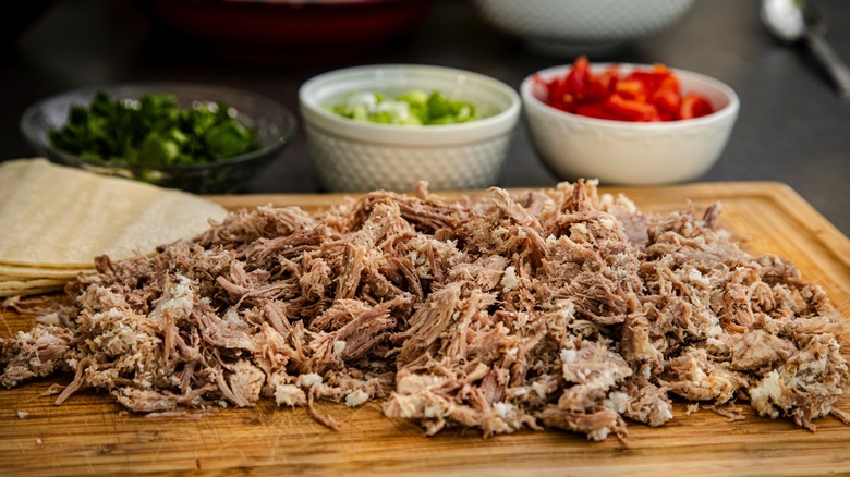 Carnitas on a board with taco toppings