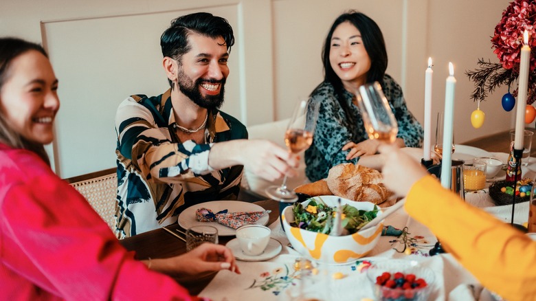 People clinking glasses over a table