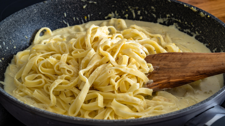 Tossing pasta in pan with Alfredo sauce