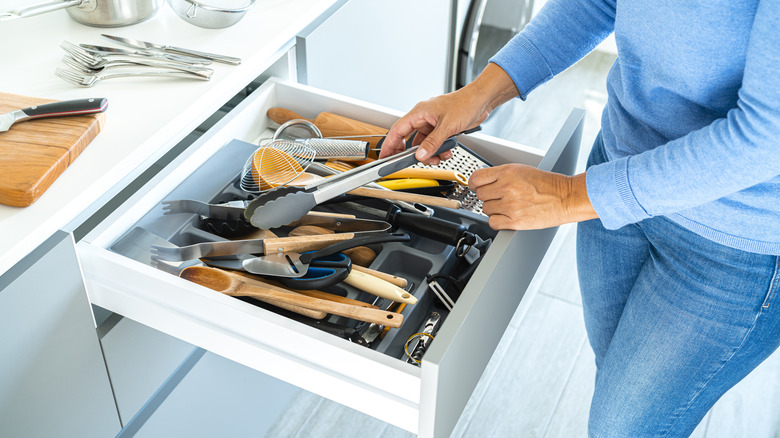 Person organizing drawer in kitchen