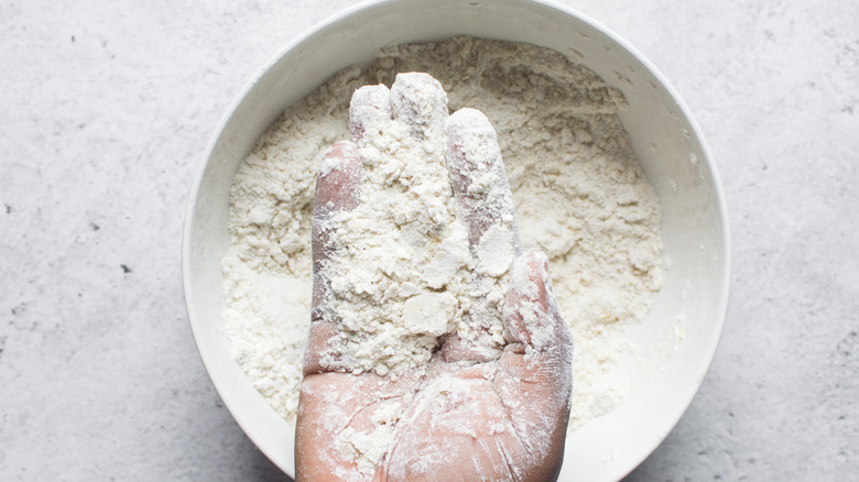 Hand holding butter and flour in a bowl