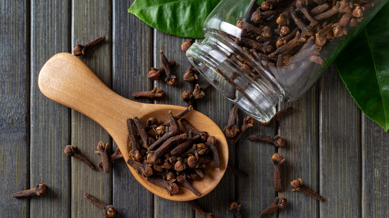 cloves spilling out of jar onto wooden spoon