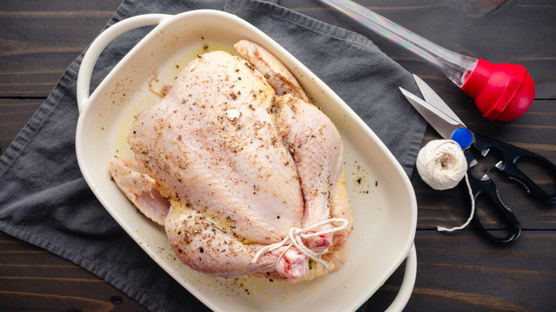 raw turkey in pan with cooking implements