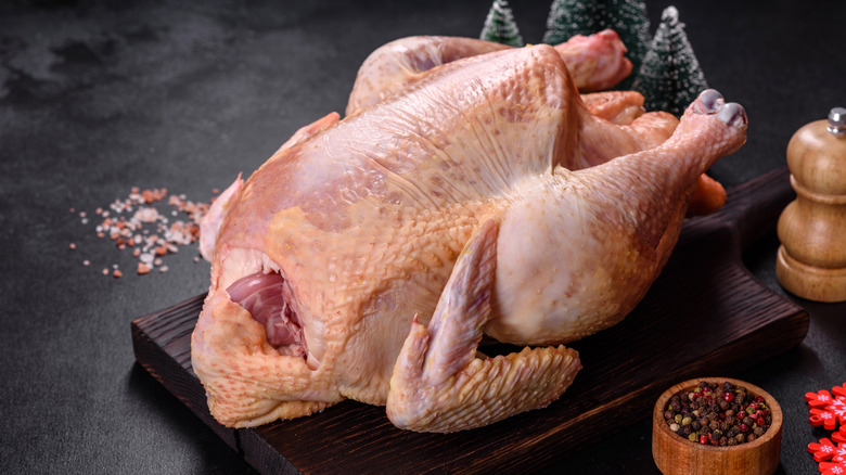raw dry turkey sitting on wooden cutting board