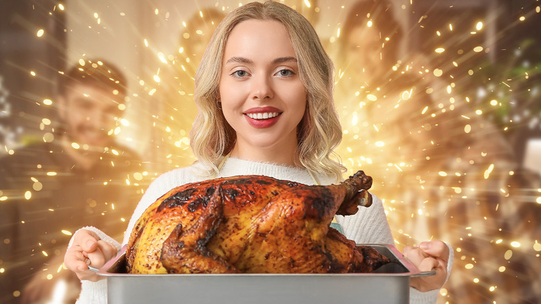 woman holding perfect turkey in pan surrounded by glow