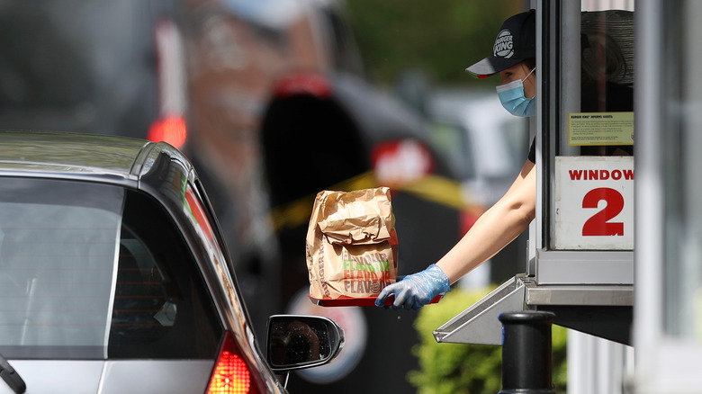 employee handing take-out bag to customer at drive-thru
