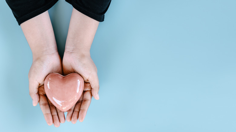 lady holding ceramic heart on blue background