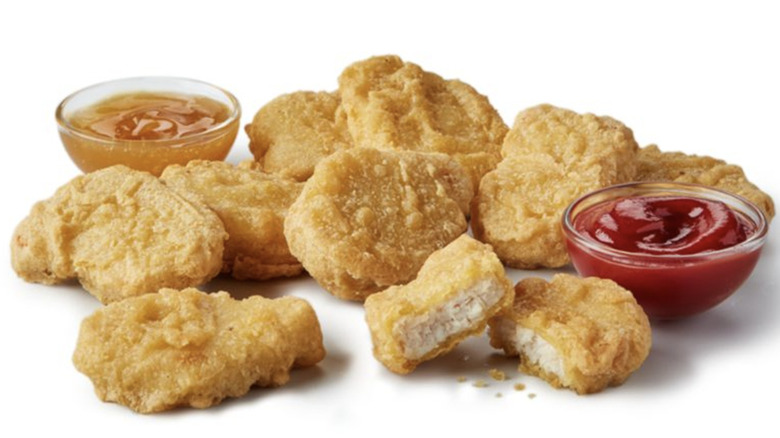 A nine-piece pack of Chicken McNuggets sits against a white background with two sauces.