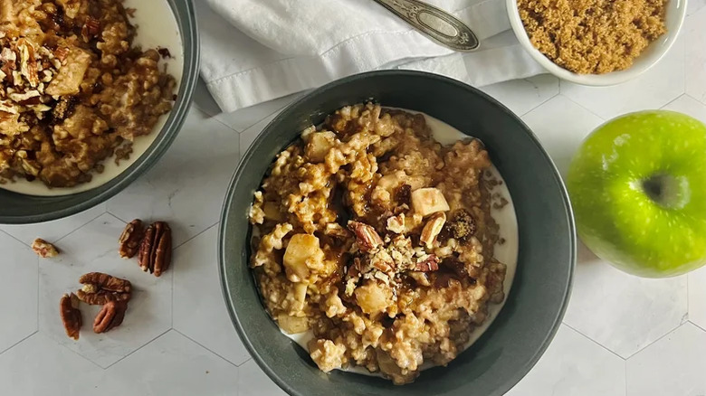 Gray bowl of apple-cinnamon slow cooker steel-cut oatmeal garnished with pecans