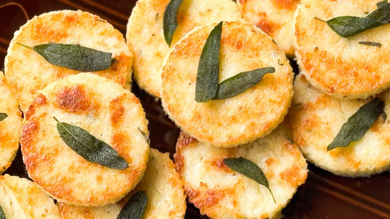 Stack of cheesy truffled grit cakes garnished with fried sage leaves