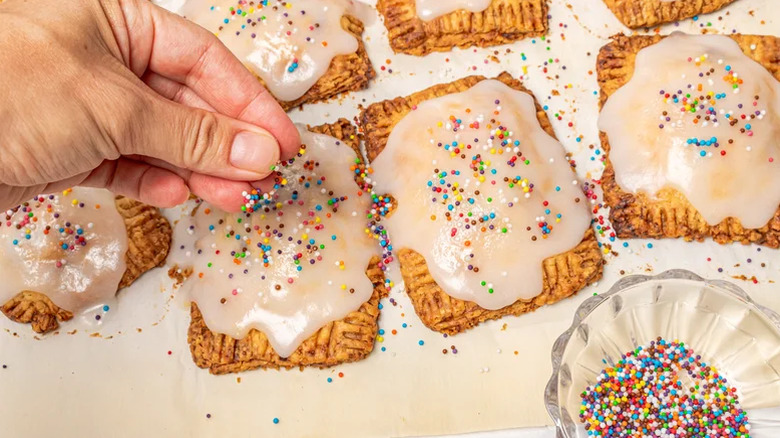 Person garnishing homemade blueberry cheesecake Pop-Tarts with sprinkles