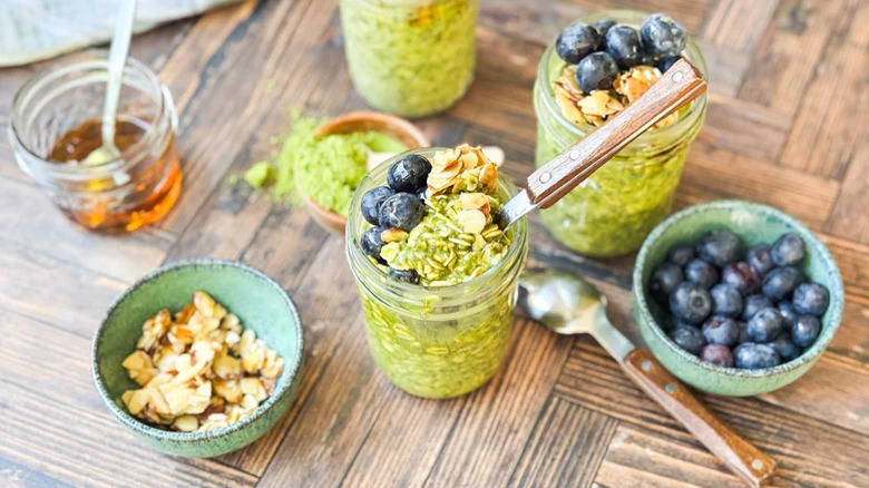 Mason jars filled with match almond overnight oats garnished with almonds and blueberries