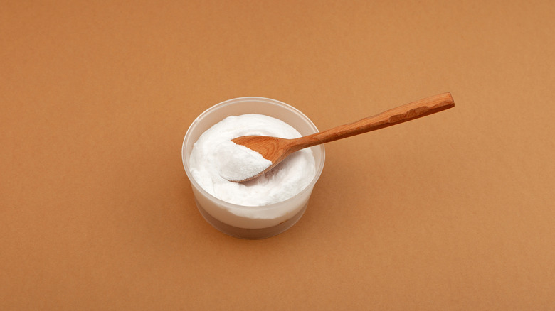 White powder phosphate in small bowl with wooden spoon