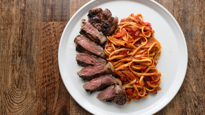 spaghetti and sliced steak on plate
