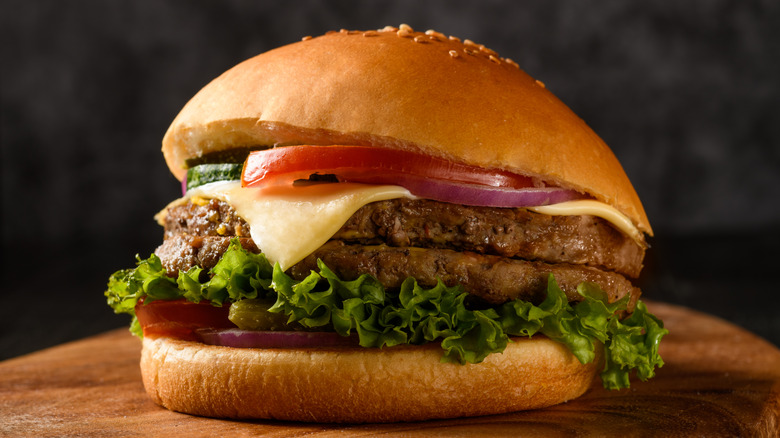 A double cheeseburger on a wooden cutting board