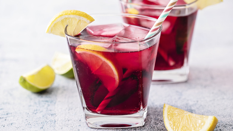 A glass of red wine and 7Up garnished with lemon and lime wedges