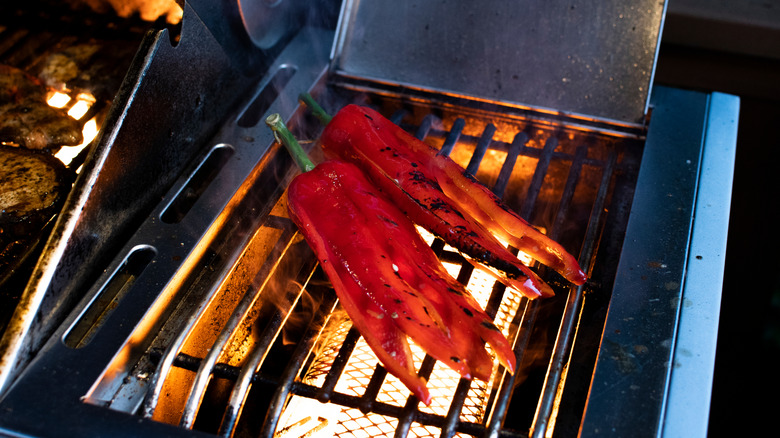 Red peppers becoming charred on barbecue grill