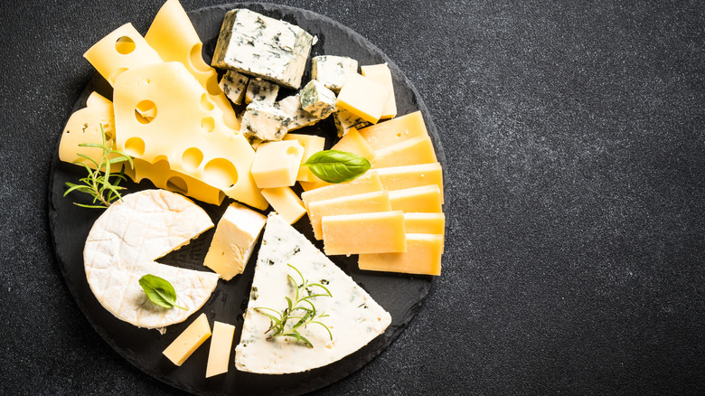 a plate of different types of cheese on black table