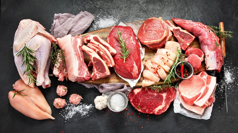 a variety of raw meat and seasoning on black table